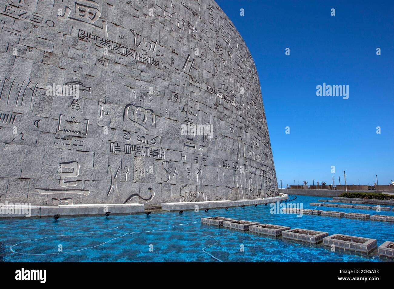 Une section des reliefs modernes gravés sur les murs extérieurs de la Bibliothèque d'Alexandrie entourée d'un étang bleu à Alexandrie en Égypte. Banque D'Images