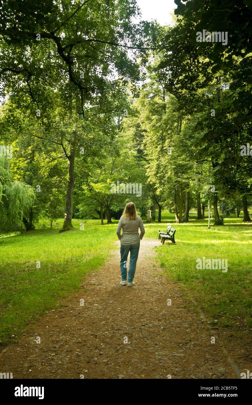femme blonde debout dans un parc entouré d'arbres et de silence, communion avec la nature et concept de recherche d'âme Banque D'Images