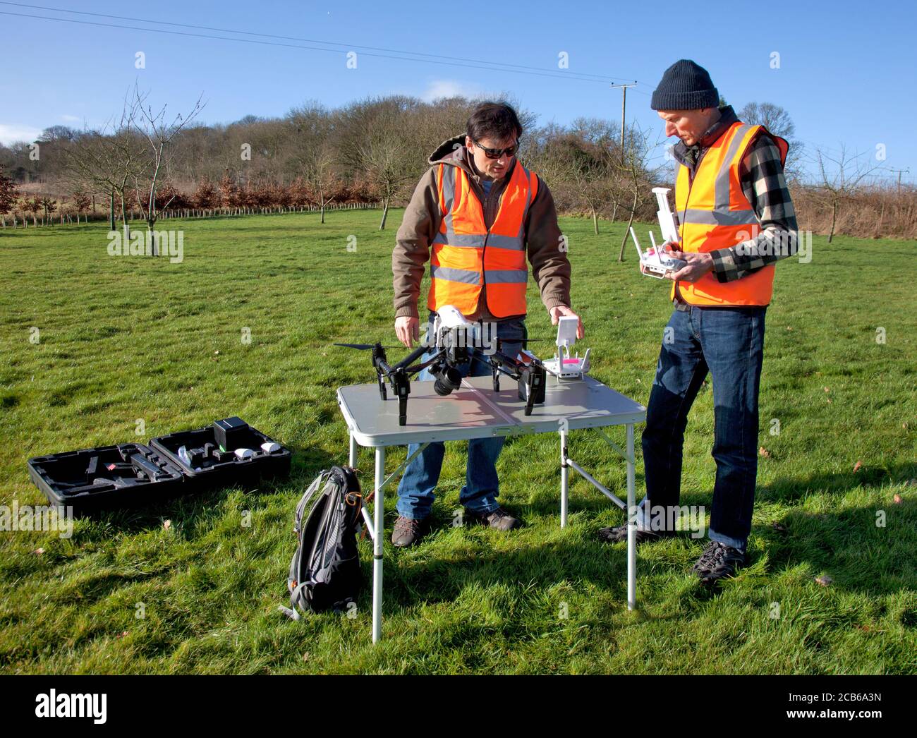 Deux hommes se préparent à voler un drone avec un appareil photo Dans un jardin de campagne dans les Cotswolds Banque D'Images