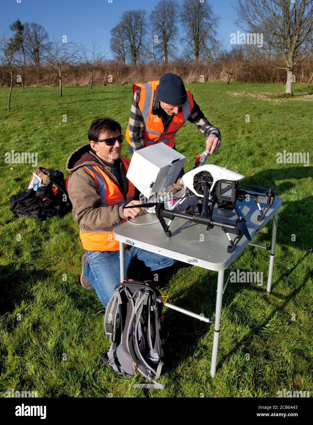 Deux hommes se préparant à voler un drone avec un appareil photo Dans un jardin de campagne dans les Cotswolds Banque D'Images