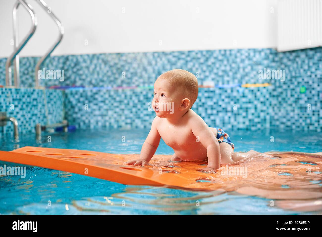 Photo horizontale d'un nageur futur. Très mignon bébé garçon est rampant  sur un tapis flottant dans la piscine essayant de garder l'équilibre.  Concept de bonne enfance Photo Stock - Alamy