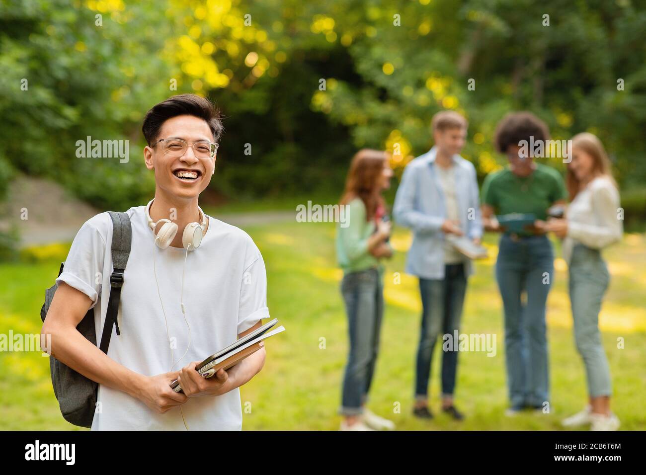 Portrait de Happy Asian Student Guy avec Workbooks et sac à dos Pose à l'extérieur Banque D'Images