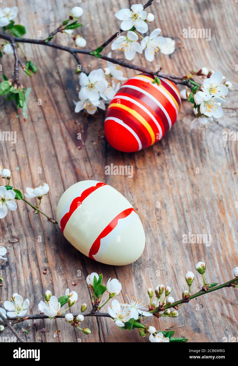 Vue imprenable sur les œufs de pâques peints en couleurs et le décor aux branches en fleur de cerisier sur une table en bois d'époque. Les vacances saisonnières traditionnelles sont encore plus belles. Banque D'Images