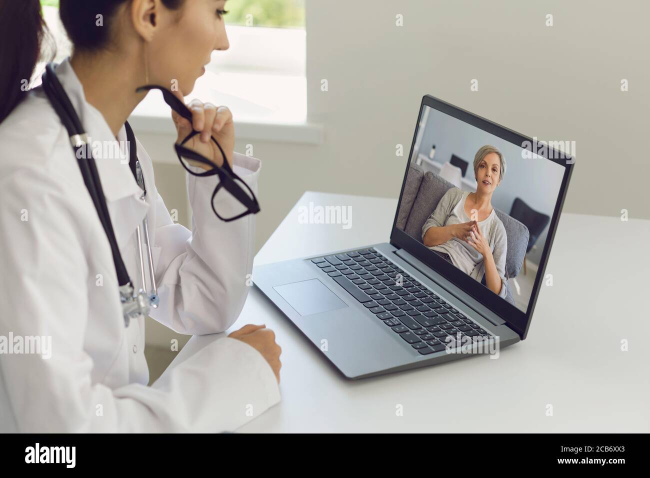 Consultation en ligne par un médecin. Une femme médecin écoute un patient âgé à l'aide d'un ordinateur portable d'appel vidéo. Banque D'Images