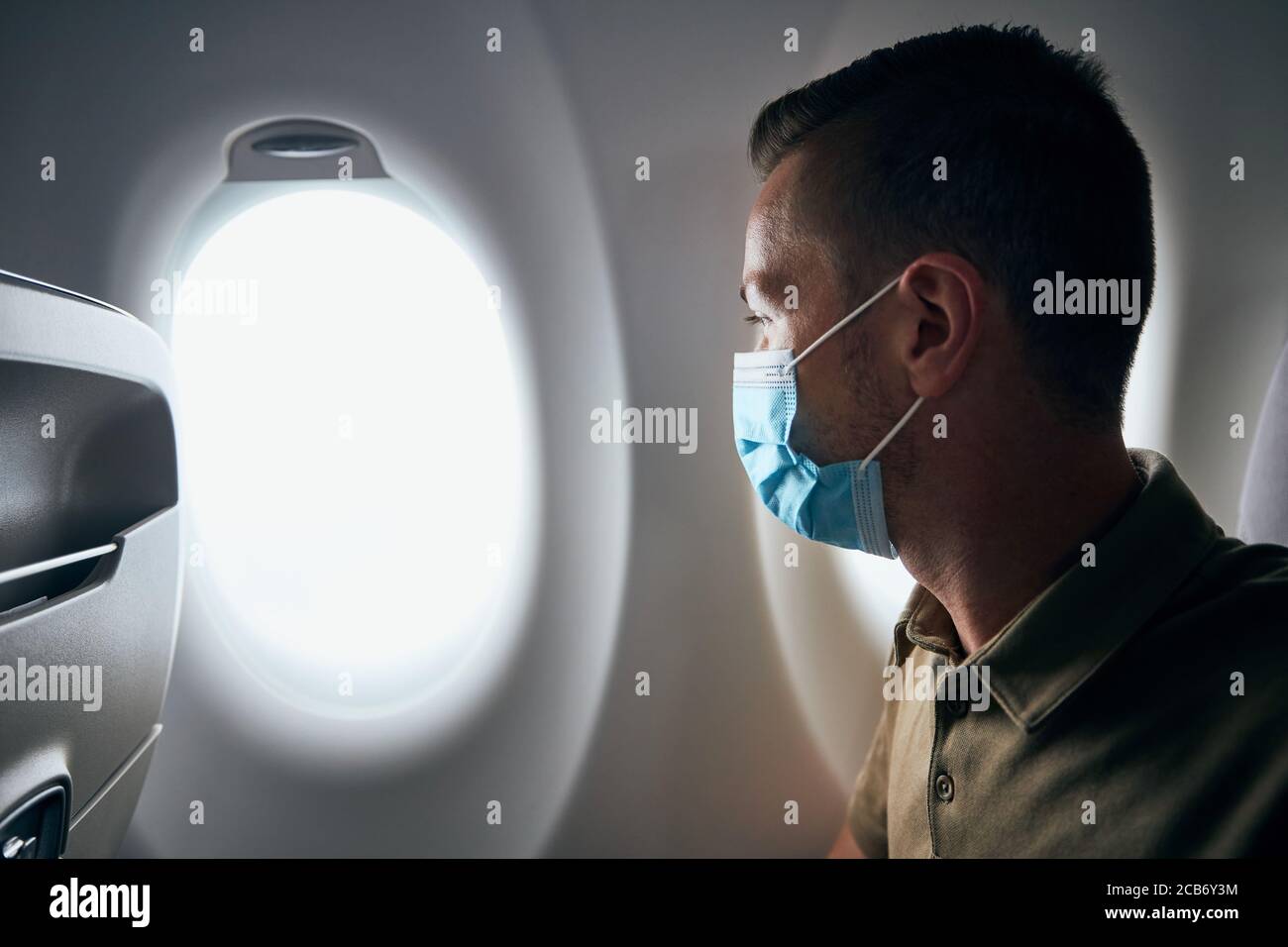 Homme portant un masque à l'intérieur de l'avion pendant le vol. Thèmes nouveau normal, coronavirus et protection personnelle. Banque D'Images