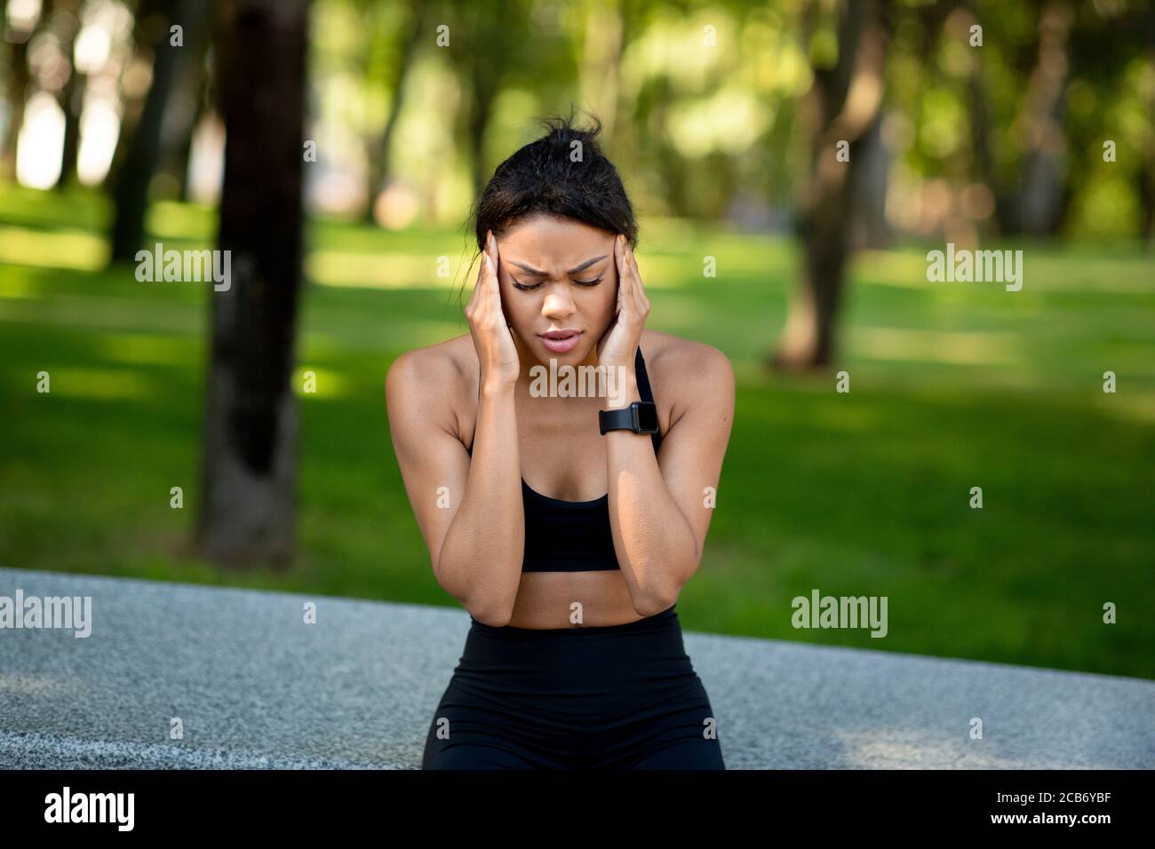 Jogging femme noire ayant des maux de tête pendant l'entraînement au parc Banque D'Images
