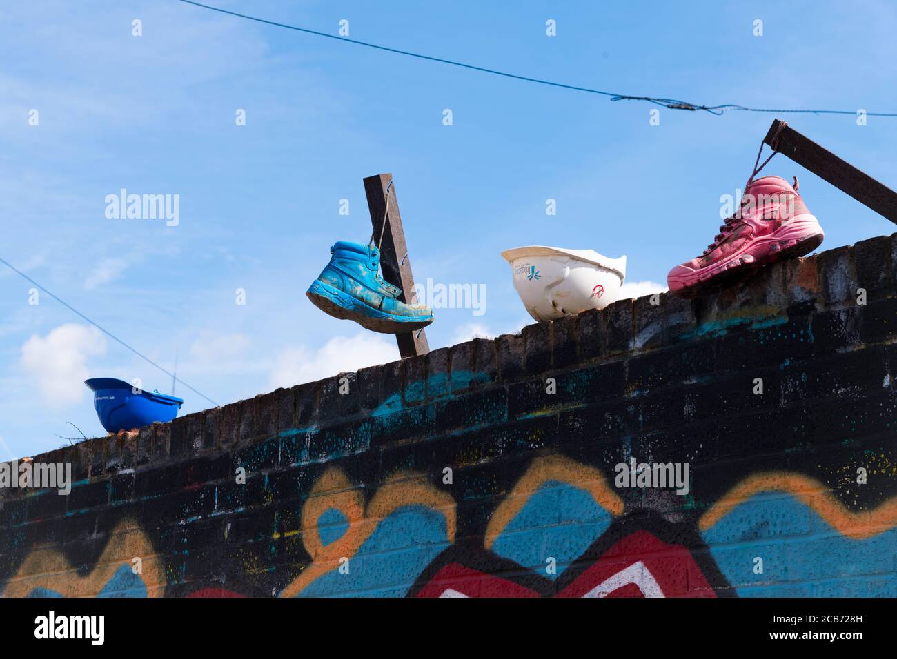 Angleterre London Stratford Park Hackney Wick graffiti art non conventionnel coloré chaussures de sport rose vert blanc bleu casques piquets muraux Banque D'Images