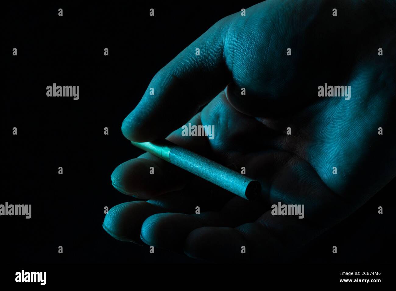 cigarette à la main sur un fond sombre concept de fumer et la toxicomanie problème social Banque D'Images