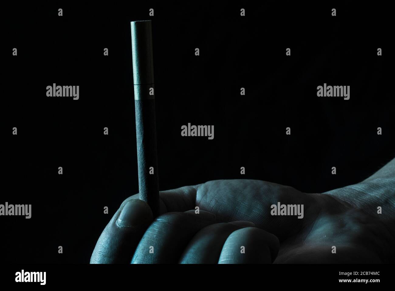 la main tient une cigarette nocive pour la santé sur une obscurité contexte un objet qui crée une dépendance et de nombreuses maladies a problème social Banque D'Images