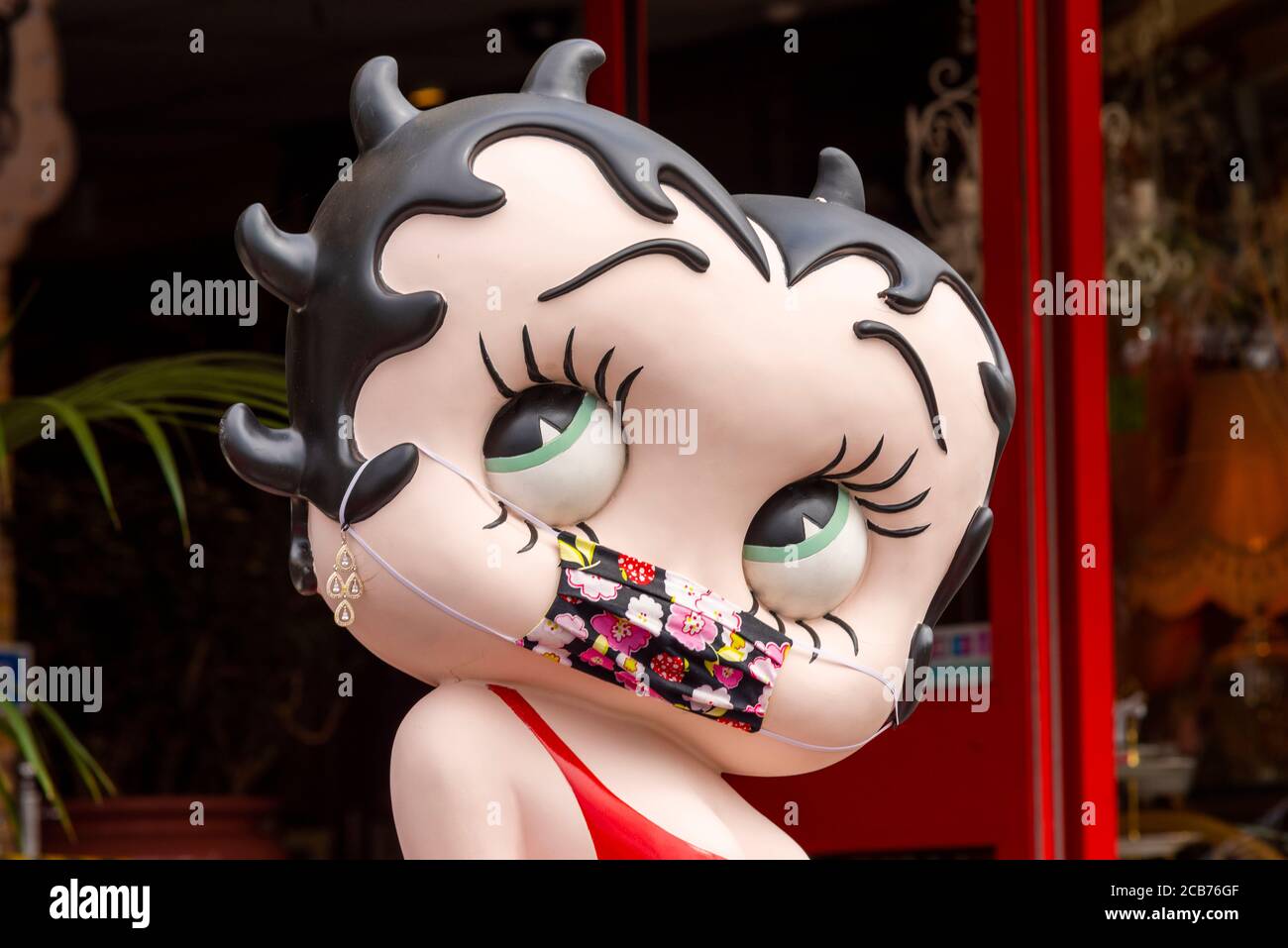 Betty Boop portant un masque COVID-19. Grande caricature de la vedette de dessin animé Max Fleischer avec un couvre-visage coronavirus. Robe rouge. Humoristique Banque D'Images