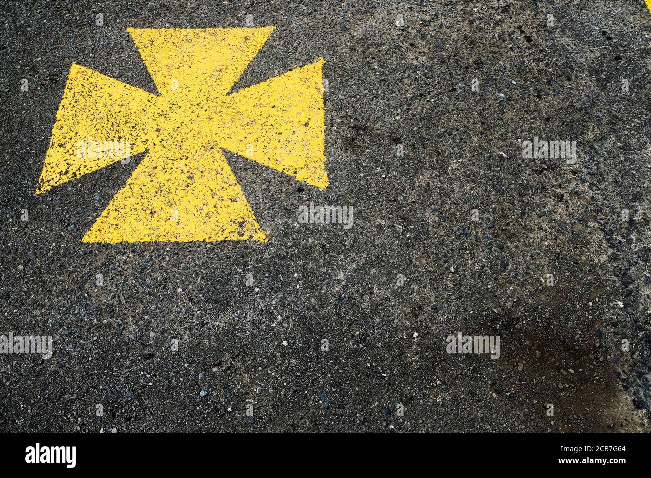 Croix maltaise jaune, aire de stationnement pour ambulance marquée du symbole jaune. Banque D'Images