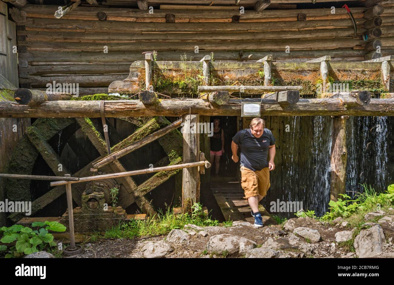 Touriste sortant sous le flume, fuite d'eau, roue d'eau surchargée au moulin historique d'eau d'Oblazy à la rivière Kvacianka, vallée de Kvacany (Kvačianska dolina), zone de Liptov, région de Zilina, Slovaquie Banque D'Images