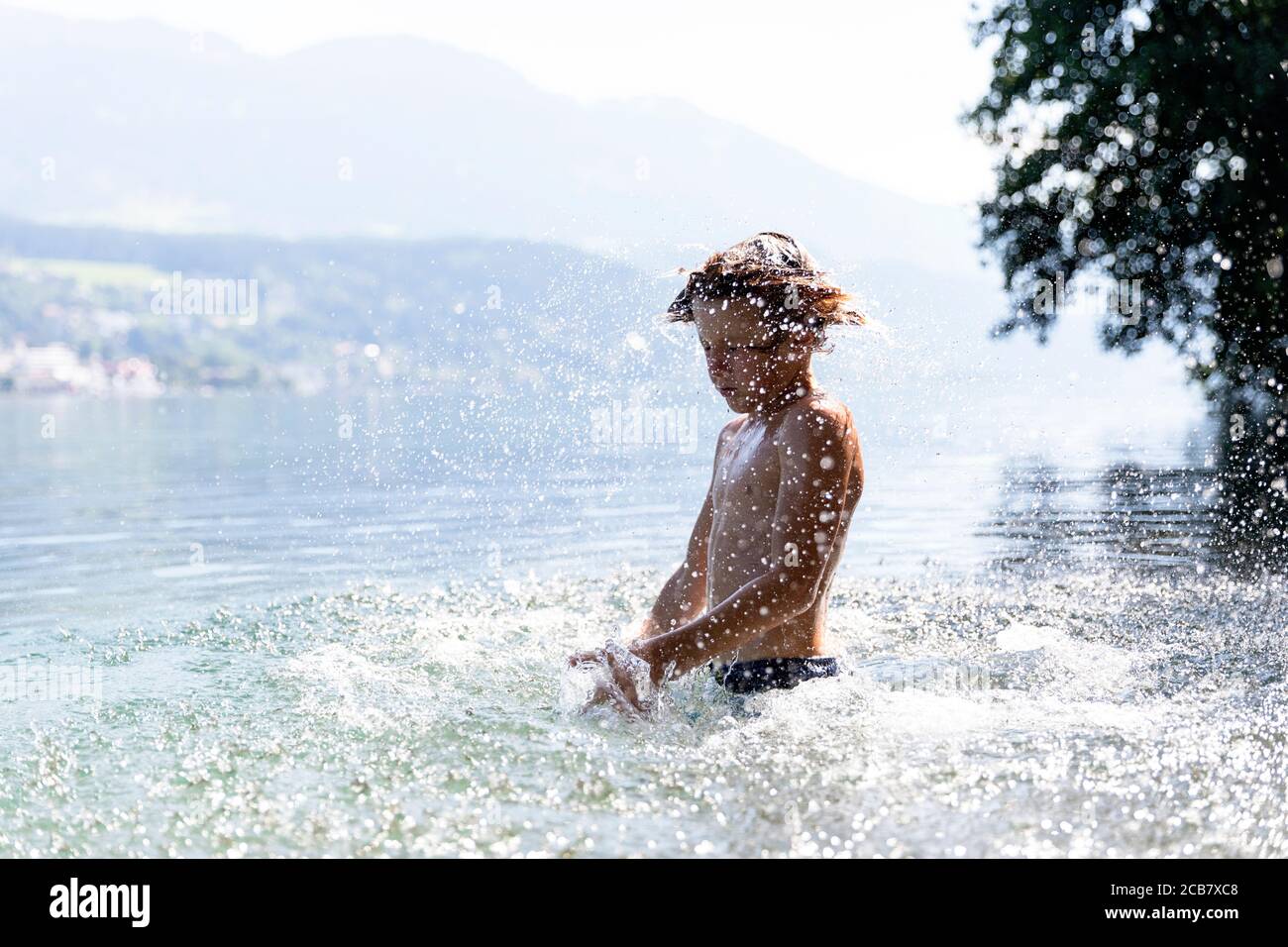 Garçon secouant la tête et éclaboussant tout autour du lac Millstatter, Millstatt, Carinthie, Autriche Banque D'Images