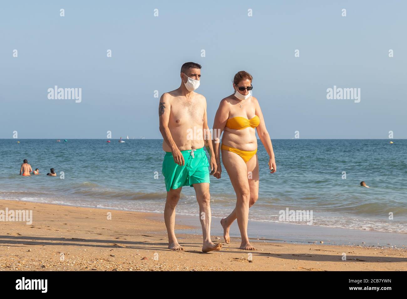 Punta Umbria, Huelva, Espagne - 7 août 2020 : couple marchant sur la plage en portant des masques protecteurs ou médicaux. Nouvelle normale en Espagne avec di social Banque D'Images