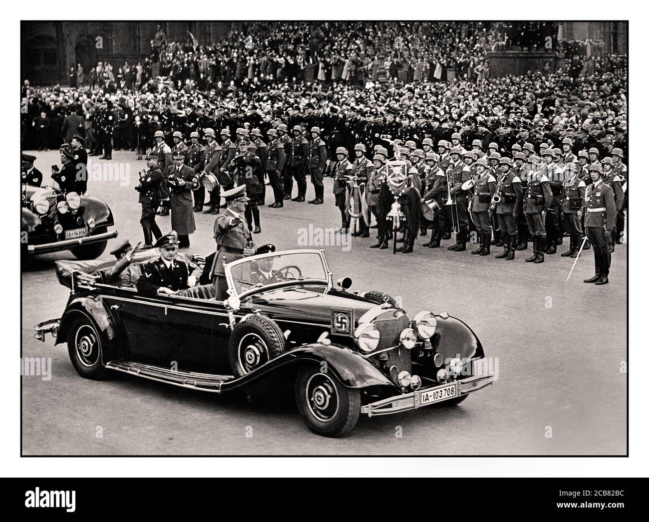 Adolf Hitler des années 1940 dans ses salutes en limousine Mercedes à toit ouvert La foule allemande dans un défilé de victoire à Berlin après Son invasion réussie de la France son personnel Liebstandarte SS 1er Panzer Division en premier plan WW2 Seconde Guerre mondiale Banque D'Images