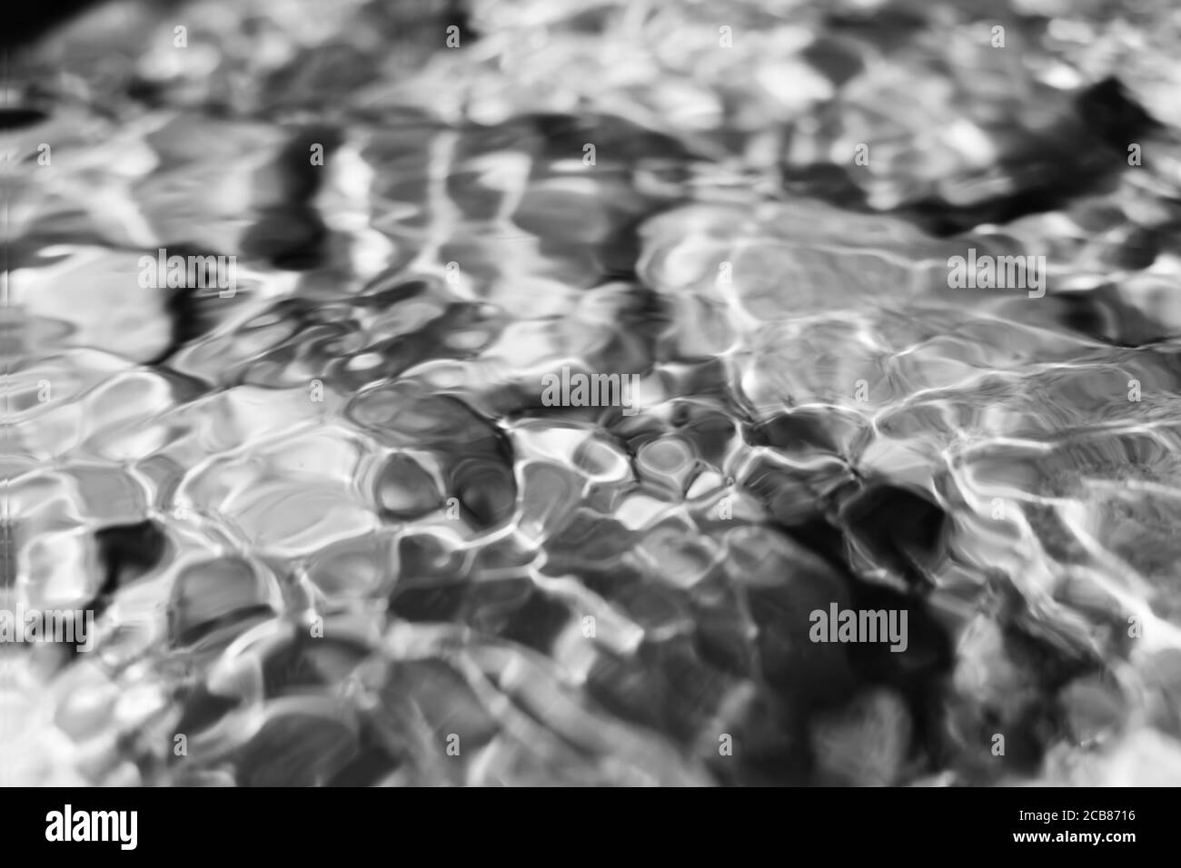 Réflexions en noir et blanc sur la surface de l'eau, surface lisse avec des bulles et des motifs circulaires. Fond noir et blanc parfait. Pierres Banque D'Images