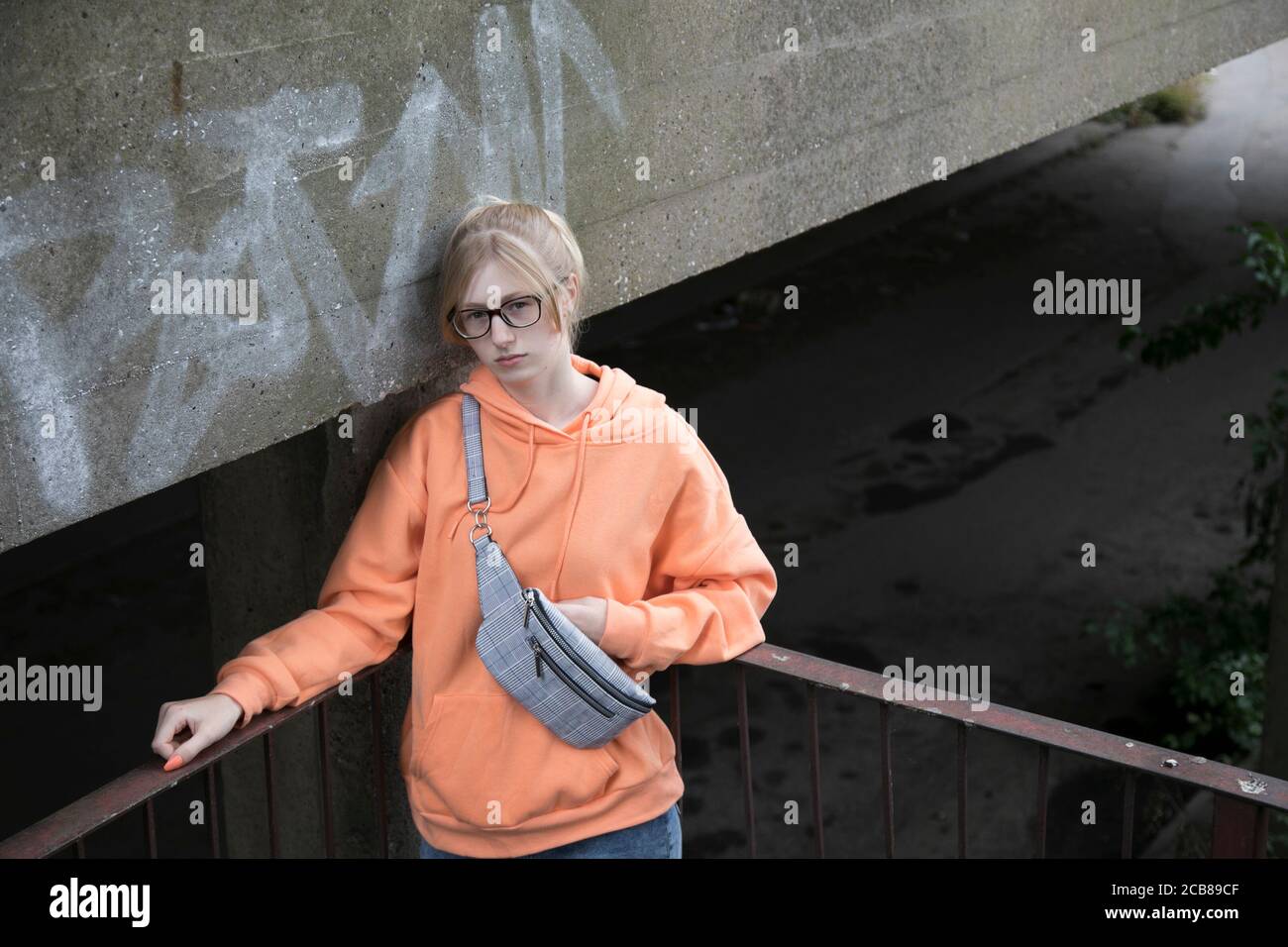 Un adolescent de race blanche blonde porte des lunettes dans les vêtements de rue ville abandonnée Banque D'Images