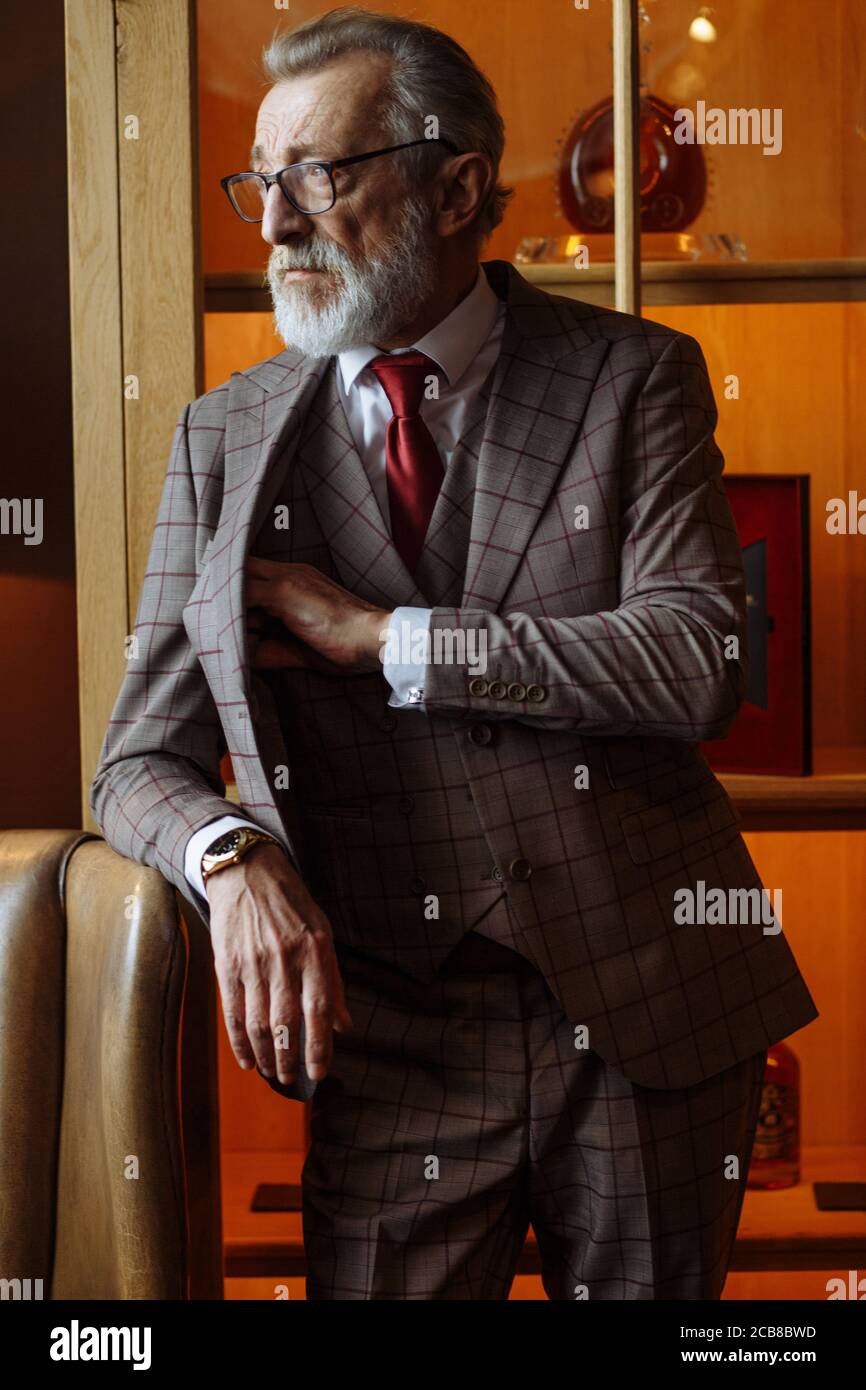 Vieux hommes d'affaires aux cheveux gris vêtus de vêtements et de lunettes,  costume avec cravate rouge, posant à l'intérieur de luxe, regardant la  caméra, bel Photo Stock - Alamy
