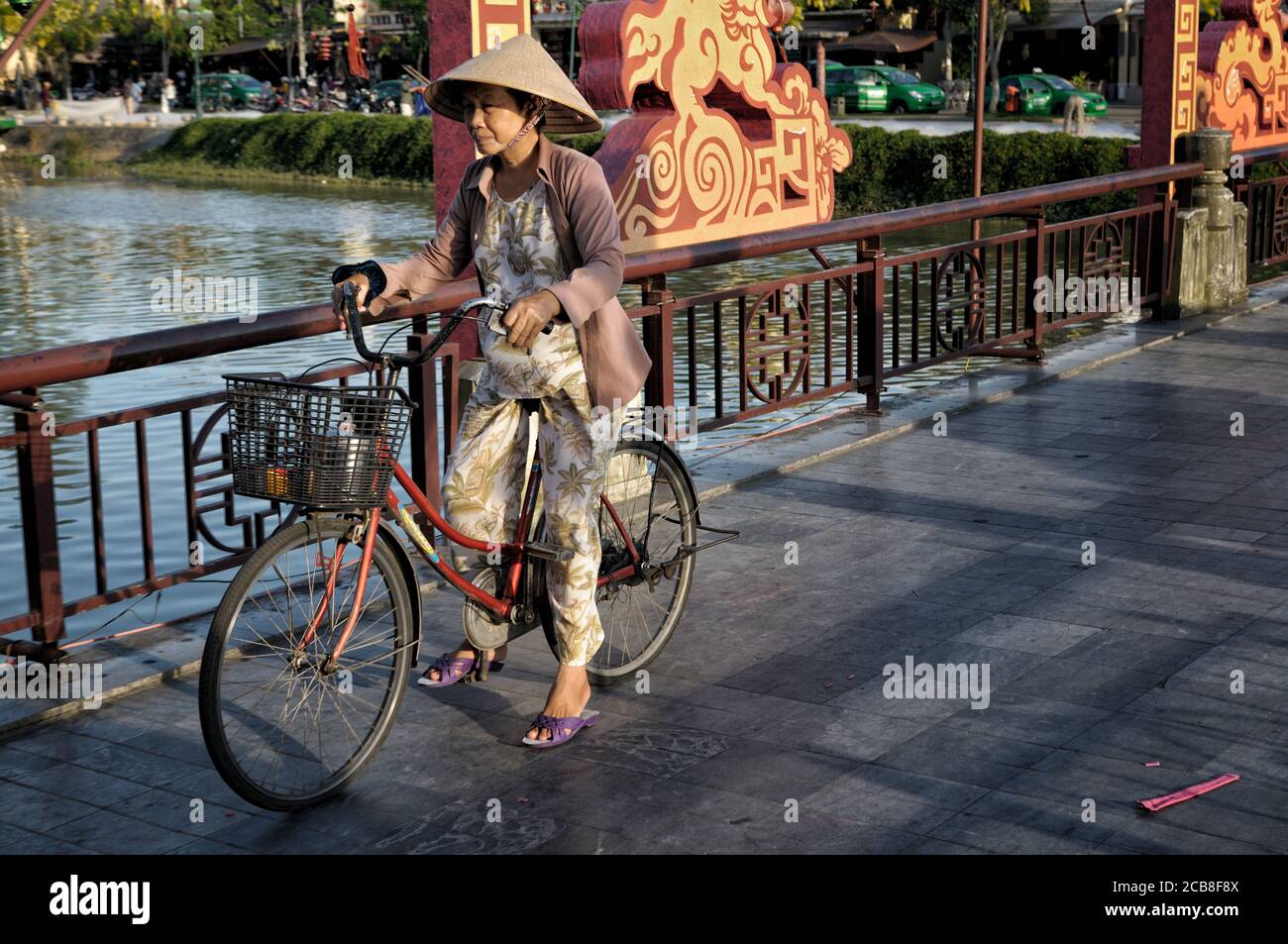 Femme pédalant sur un pont à Hoi an (Pont des lumières), Vietnam Banque D'Images