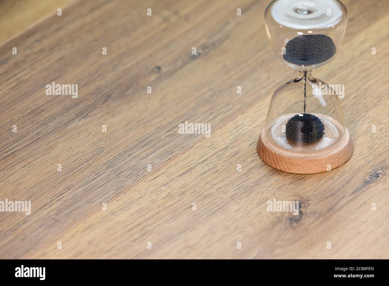 time concept, sablier avec sable noir sur table en bois Banque D'Images