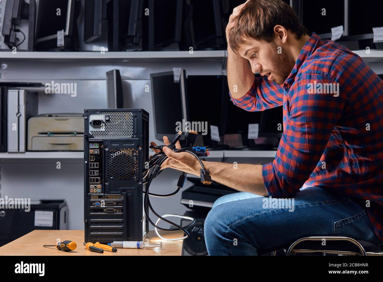 perplexe, un homme confus tenant de nombreux fils et se grattant la tête en oubliant où les connecter, gros plan sur une photo de côté Banque D'Images