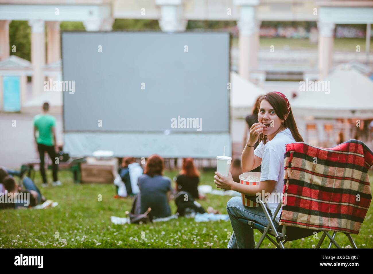 femme assise dans une chaise de camping et regardant un film au cinéma en plein air Banque D'Images