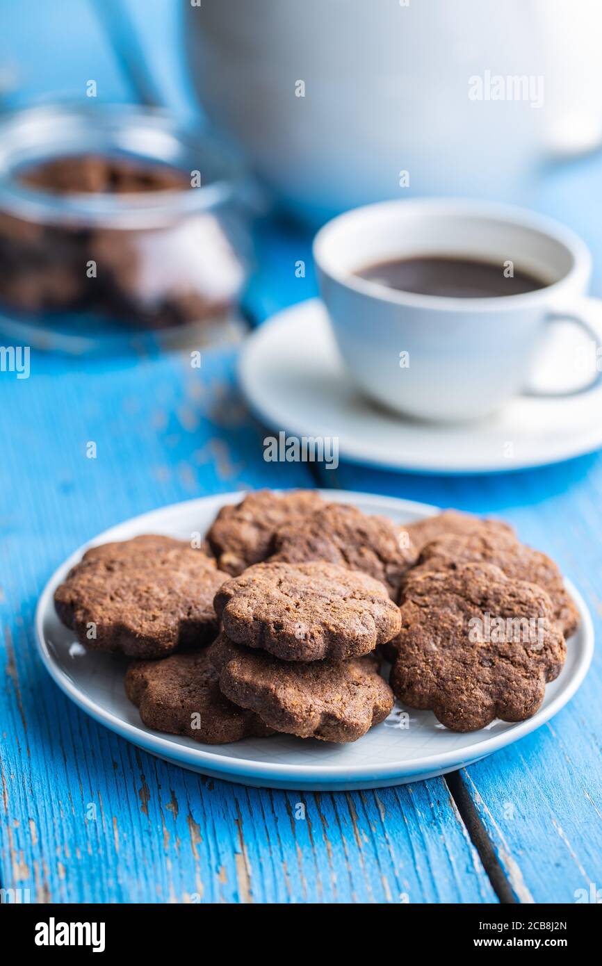 Biscuits sucrés. Biscuits croquants au chocolat en forme de fleur sur l'assiette sur table en bois bleu. Banque D'Images