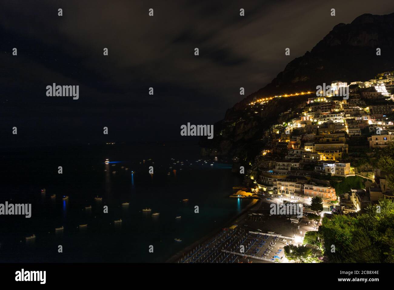 Vue sur la ville de Positano et la plage la nuit pendant une soirée nuageux avec quelques étoiles, côte amalfitaine, sud de l'Italie. Banque D'Images