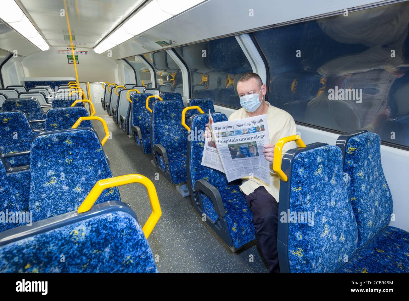 Un homme seul dans un train vide lit les informations sur le coronavirus du journal du Sydney Morning Herald à Sydney, en Australie, alors que la population abandonne les lieux publics en prévision d'un confinement à l'échelle de la ville. De nombreuses entreprises et lieux de rassemblement classés par le gouvernement comme non essentiels - comme les pubs, les restaurants, les plages et les lieux de culte - ont été considérés comme hors-limites jusqu'à nouvel ordre. (Modèle validé) Banque D'Images