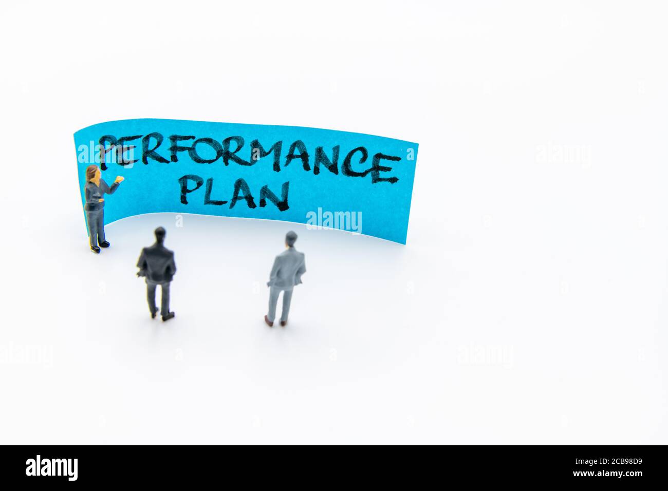 Réunion de présentation avec des figurines miniatures posées comme des hommes d'affaires debout En face de la note post-IT avec le message manuscrit du Plan de rendement po Banque D'Images