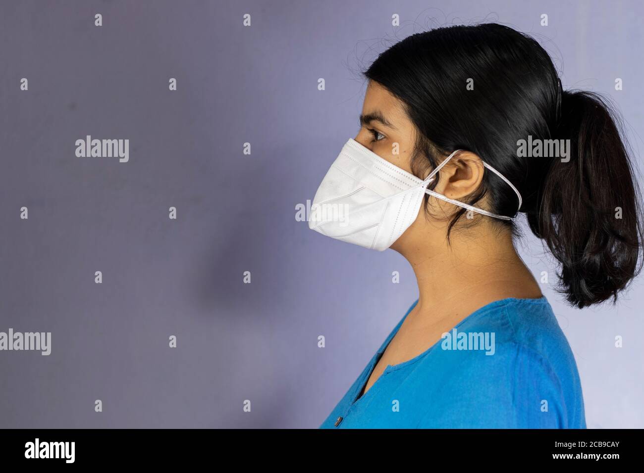 Face latérale d'une femme indienne portant un masque nasal N-95 pour la protection contre le virus corona ou le covid-19 sur fond blanc Banque D'Images