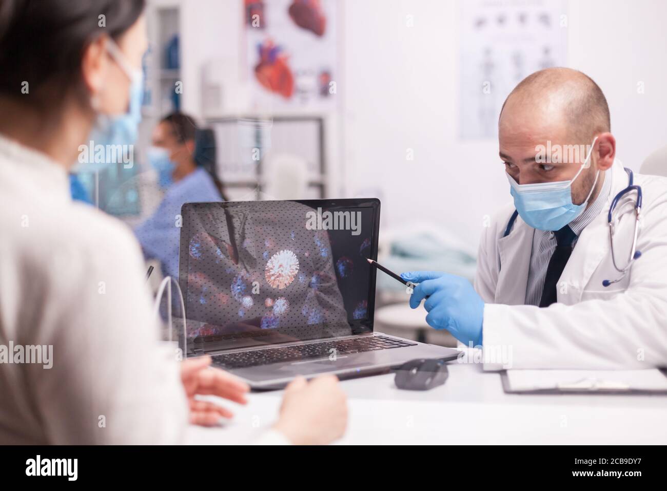 Médecin pointant vers la représentation du coronavirus sur un écran d'ordinateur portable, informant les patients de la maladie COVID-19 Banque D'Images Médecin pointant vers la représentation du coronavirus sur un écran d'ordinateur portable, informant les patients de la maladie COVID-19 Banque D'Images