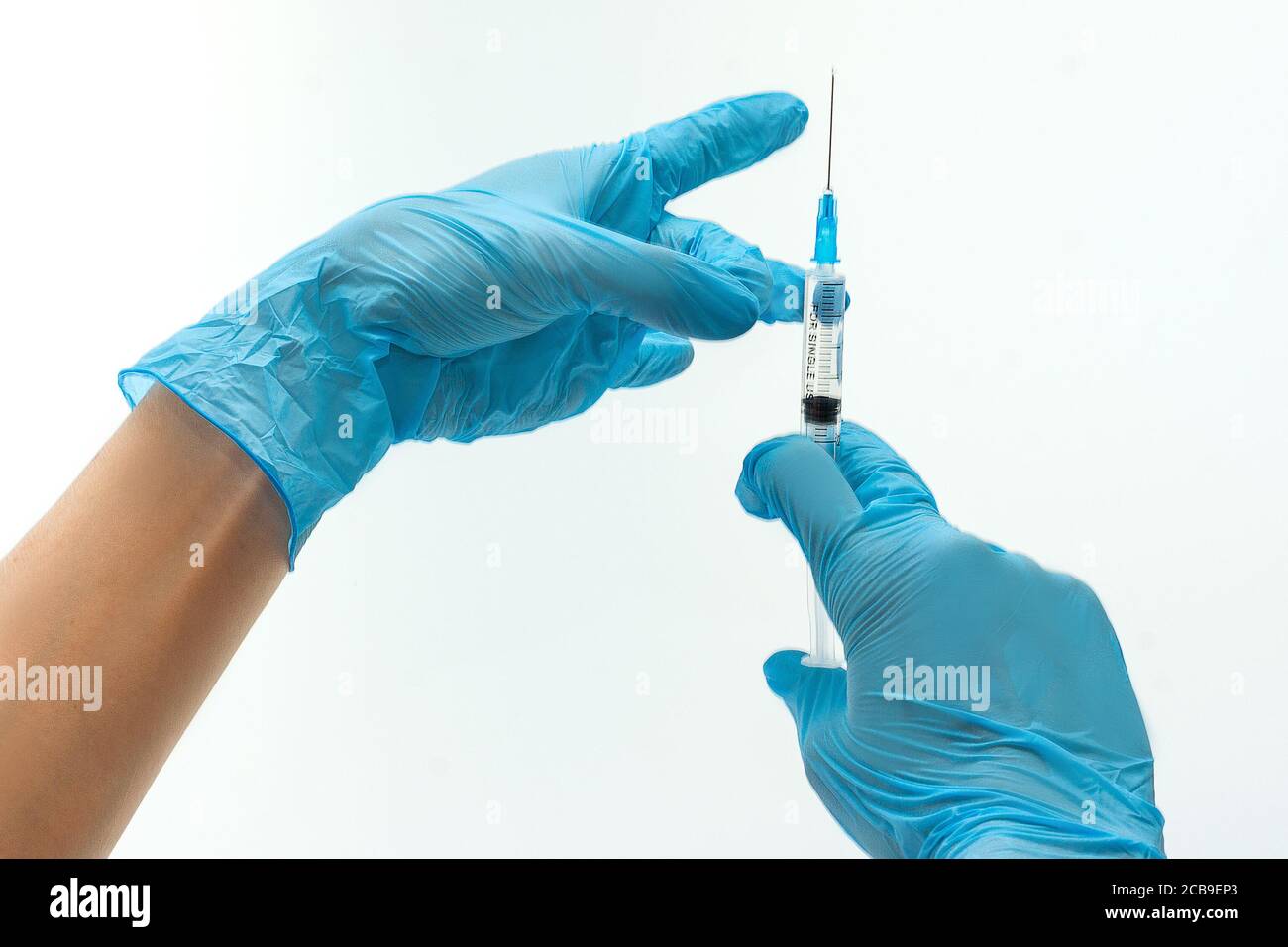 Mains de médecin dans les gants en latex bleu holding syringe. Objets isolé sur fond blanc Banque D'Images