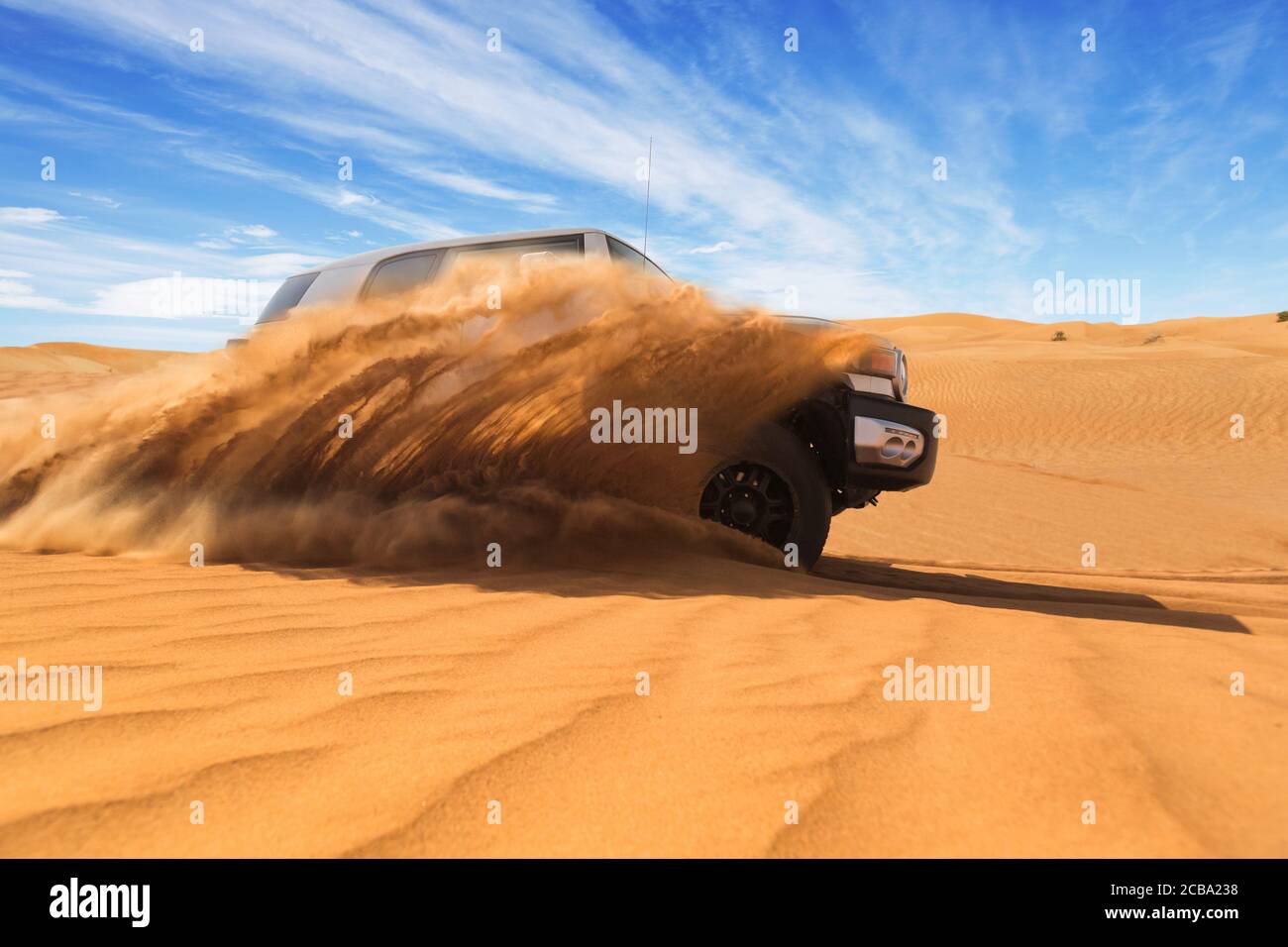 Dérive hors de la voiture 4x4 dans le désert. Geler le mouvement de l'explosion de la poudre de sable dans l'air. Activité d'action et de lasure. Banque D'Images