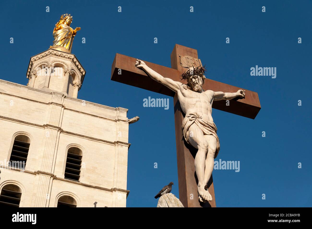 En premier plan la statue de Jésus-Christ en croix, en arrière-plan la cathédrale d'Avignon (cathédrale notre-Dame des Doms), est une ca catholique romaine Banque D'Images