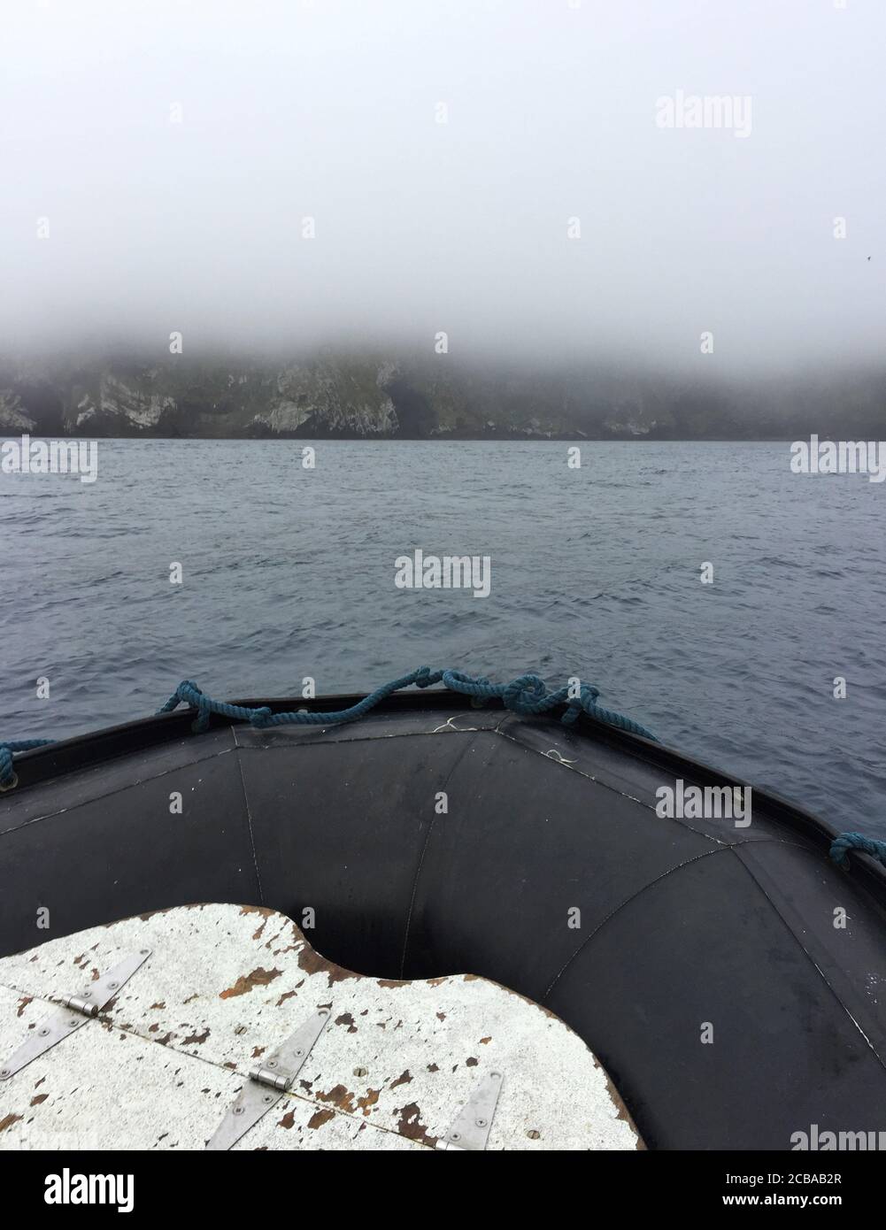 Vue d'un zodiaque à une île volcanique inhabitée dans la brume, Nouvelle-Zélande, îles Antipodes Banque D'Images