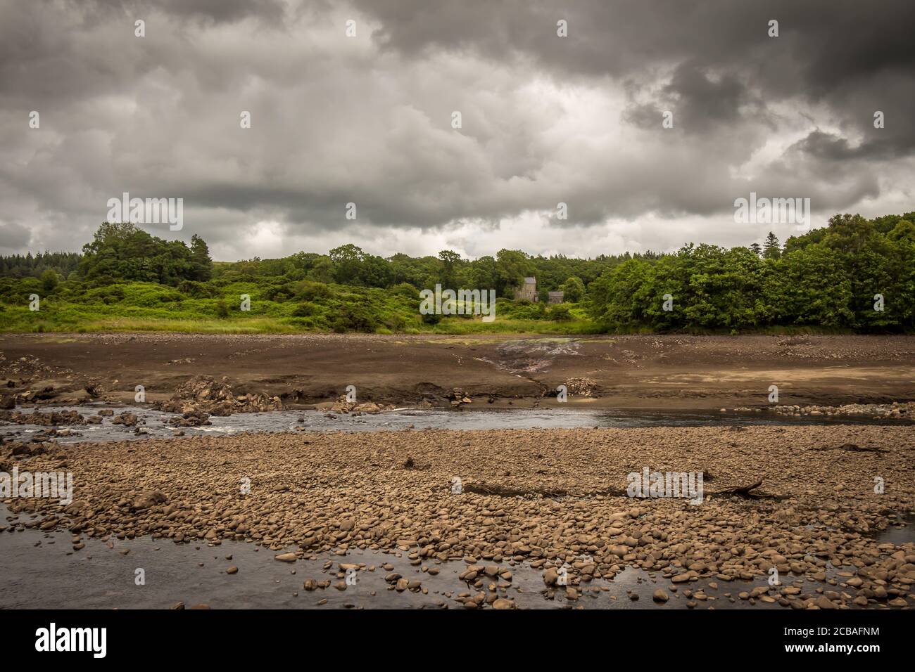 L'eau originale du lit de rivière Ken exposée en raison du barrage d'Earlstoun et du Loch / réservoir, étant drainé, avec le château d'Earlstoun en arrière-plan, Gallowa Banque D'Images