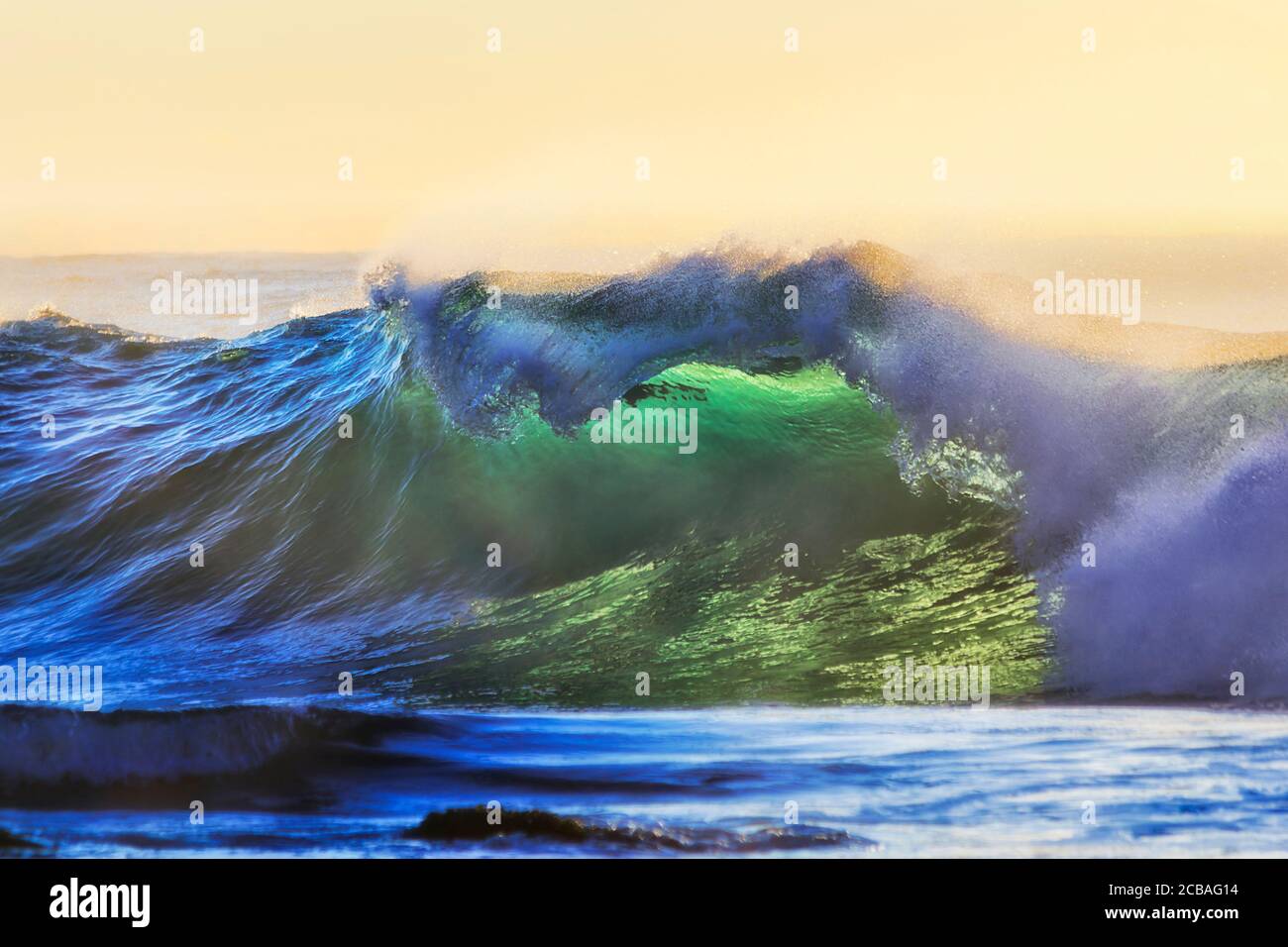 Forte vague se formant comme une grotte au large de la plage de Bronte, dans la banlieue est de Sydney, au lever du soleil dans une douce lumière du matin. Banque D'Images