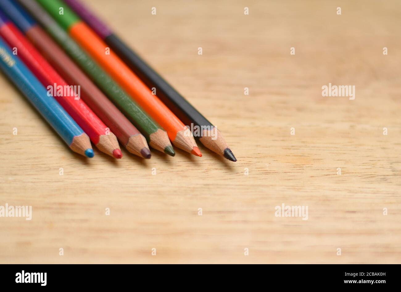 Résumé plat / disposition avec crayons de couleur aiguisés placés sur une planche en bois. Les couleurs bleu, rouge, orange, vert, noir sont visibles ici Banque D'Images