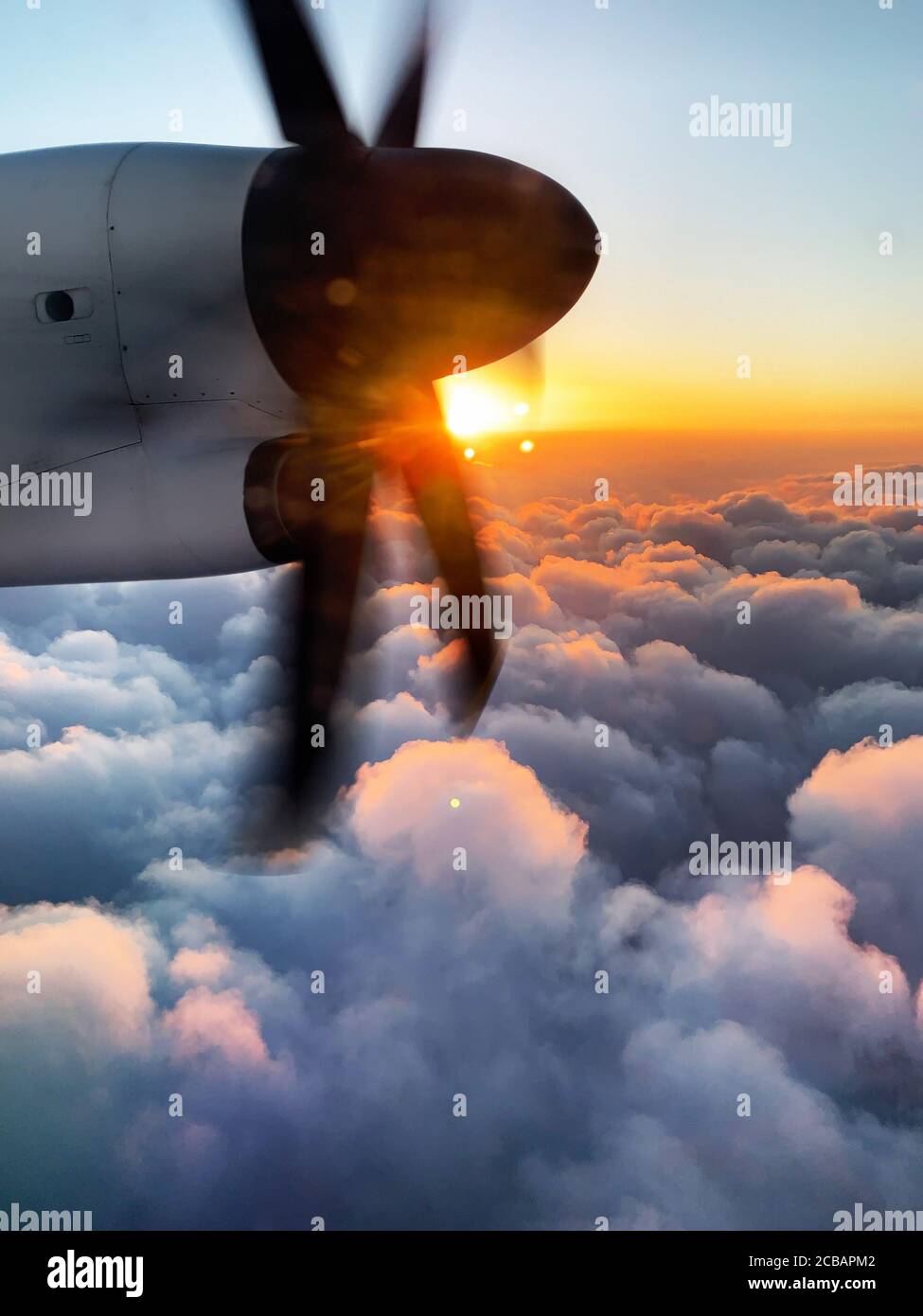 Vue romantique depuis la fenêtre d'un vol en hélice dans le soleil levant pendant un vol au-dessus des nuages. Banque D'Images