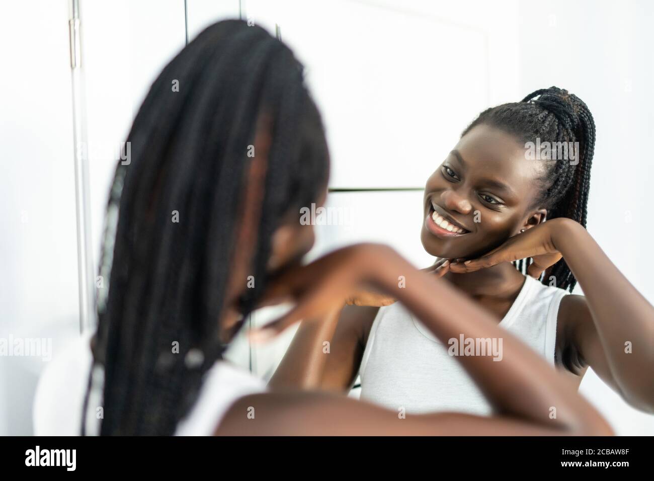 Femme africaine après la douche enveloppée dans une serviette regardant dans le miroir j'ai trouvé des rides faciales les lignes faciales se sentent inquiets d'avoir des problèmes de peau besoin d'un cosmétologue Banque D'Images