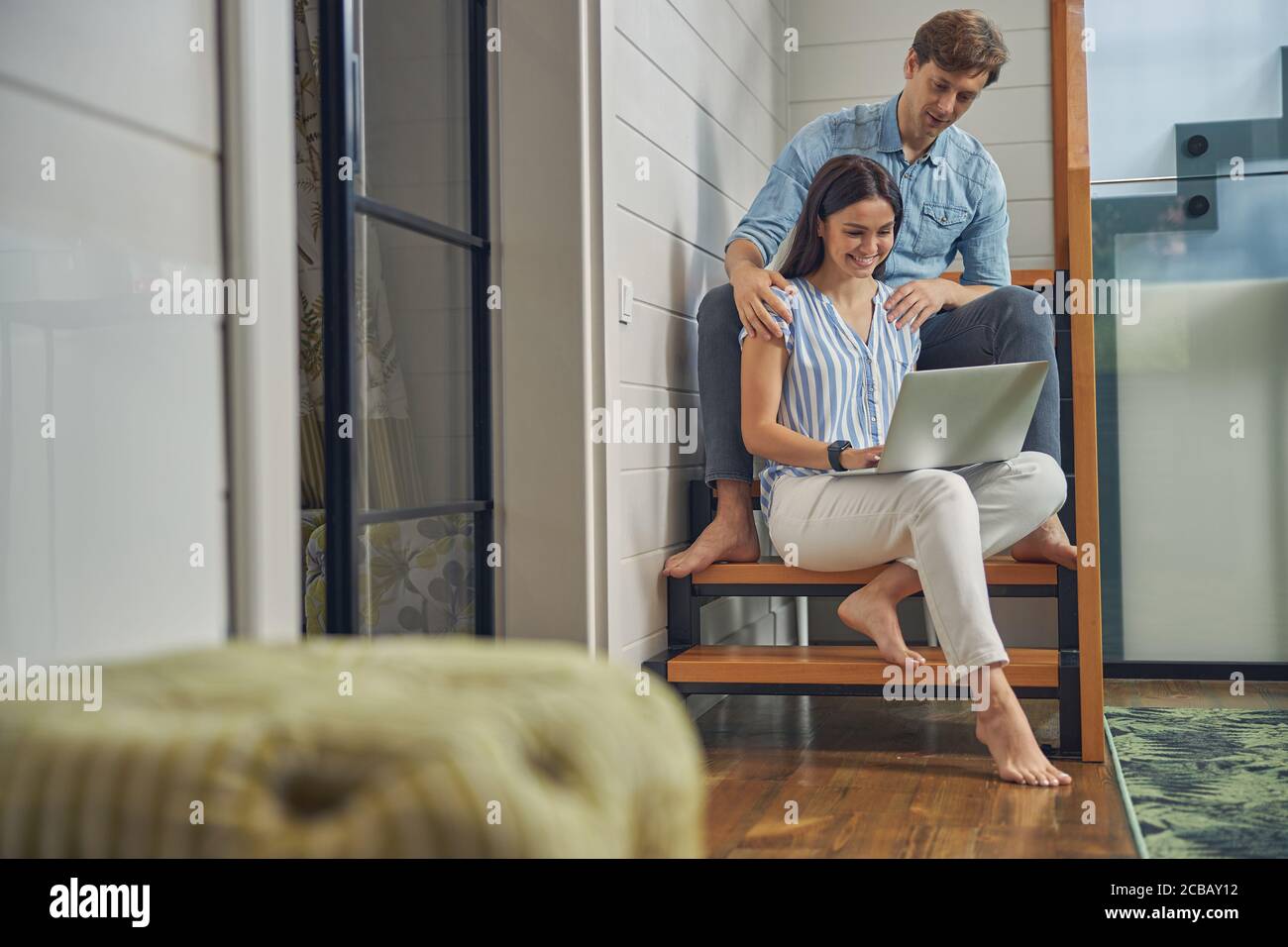 Jeune couple se détendant dans une maison luxueuse avec ordinateur Banque D'Images
