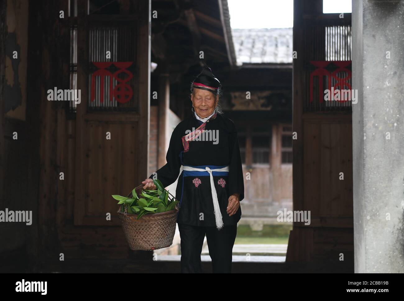 (200812) -- NINGDE, le 12 août 2020 (Xinhua) -- Zhong Lianjiao sort de sa maison au village Banyueli dans le comté de Xiapu, dans la province de Fujian, au sud-est de la Chine, le 5 août 2020. Il est courant de voir Zhong Lianjiao, une femme de 89 ans du groupe ethnique She toujours dans les costumes traditionnels She, présenter les cultures de son groupe ethnique aux touristes visitant l'ancien village Banyueli. Vivant dans le village depuis des décennies, Zhong s'efforce de promouvoir le tourisme du village en introduisant les cultures locales aux touristes. Banyueli est un village où les reliques culturelles et les coutumes populaires de elle sont Banque D'Images