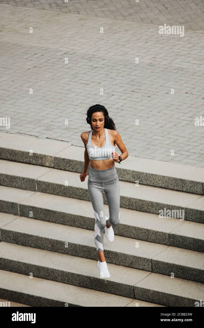 Vue en grand angle d'une femme sportive en train de courir à l'extérieur. Femme de sport courant le matin. Banque D'Images