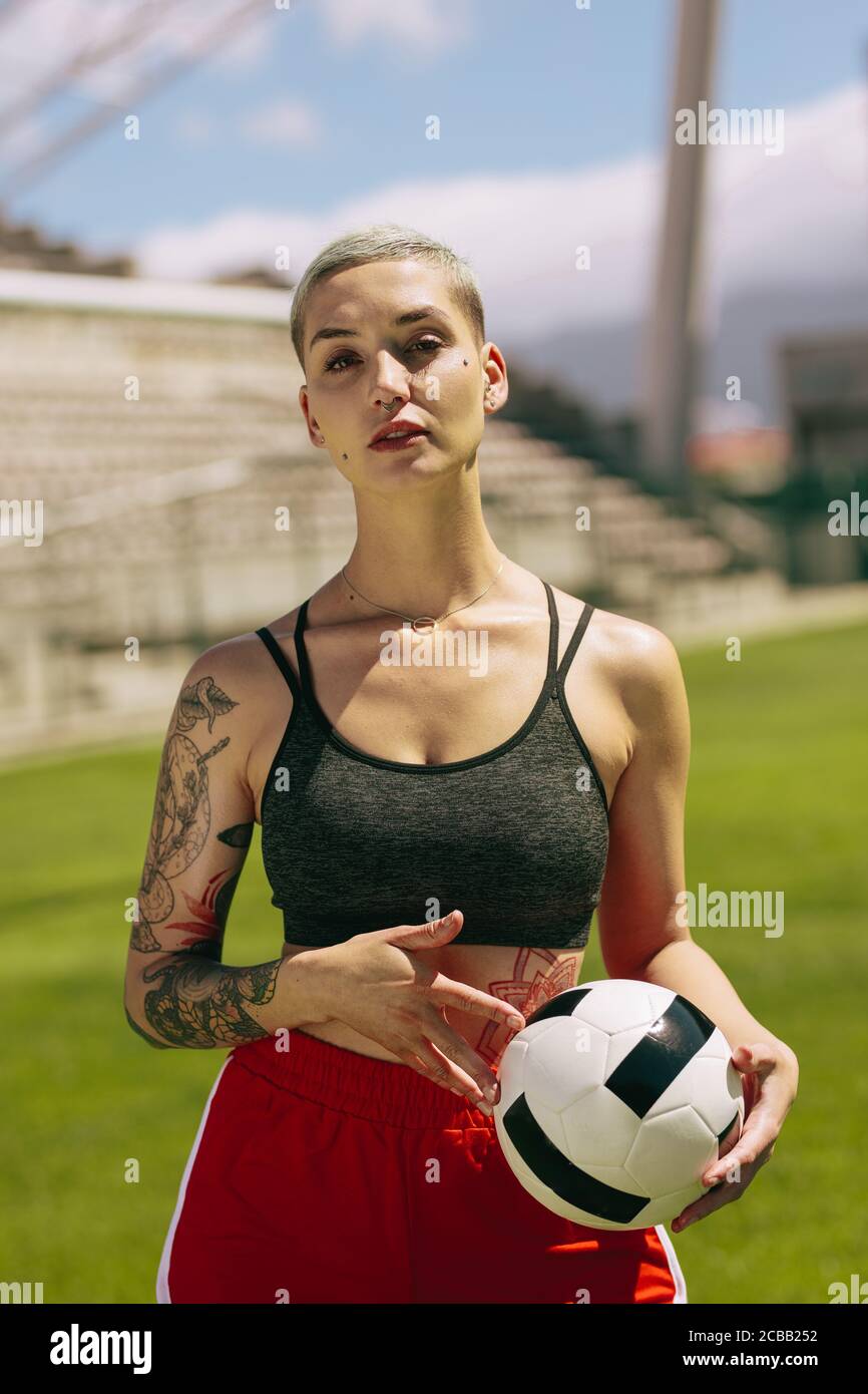 Portrait d'une joueuse de football féminine tenant une balle sur le terrain de football. Femme tenant une balle et regardant la caméra sur le terrain de football Banque D'Images