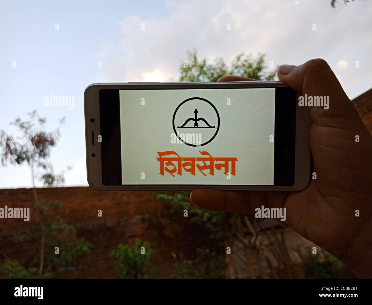 DISTRICT KATNI, INDE - 28 MAI 2020 : une dame indienne tenant un smartphone avec le symbole Shiv Sena à l'écran, parti politique incorporé par la Banque D'Images