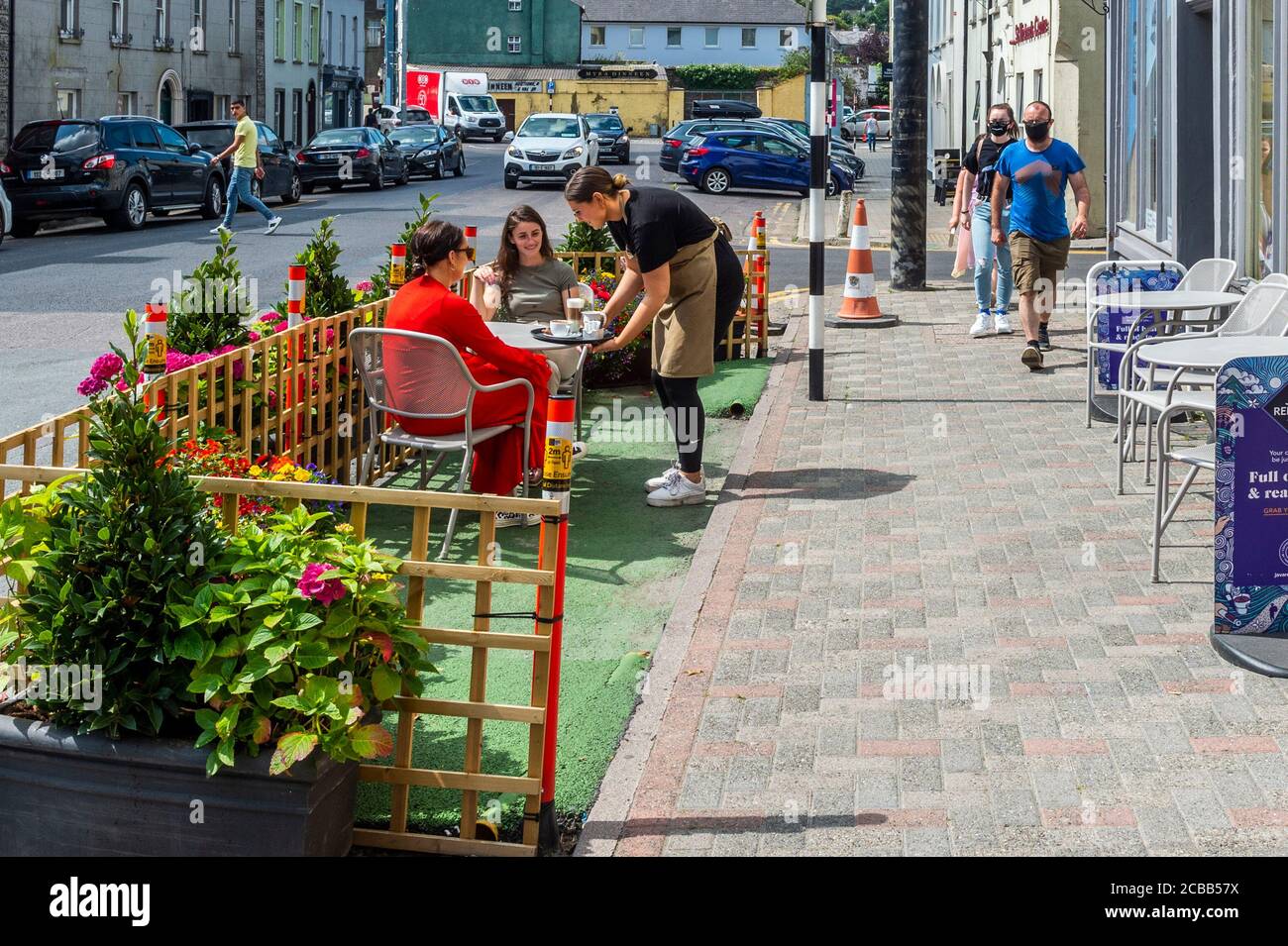 Bandon, West Cork, Irlande. 12 août 2020. Les places en plein air dans les cafés sont en train de devenir la nouvelle norme avec la pandémie COVID-19. Une serveuse sert deux clients à l'extérieur d'un café à Bandon cet après-midi. Crédit : AG News/Alay Live News Banque D'Images