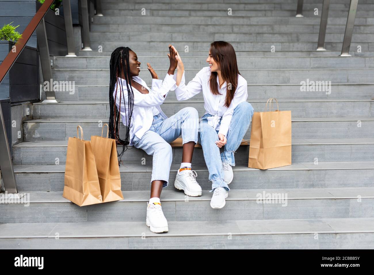 Deux meilleurs amis après avoir fait du shopping. Jeunes filles assis sur les escaliers et parlant. Banque D'Images