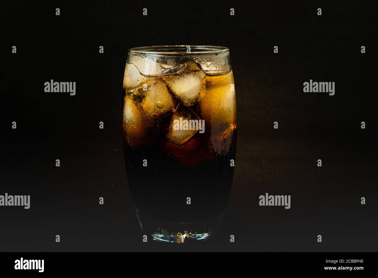 Un verre frais de boisson au cola avec de la glace, des bulles et du fizz. Coca-Cola en verre avec des glaçons isolés sur fond sombre. Concept de boisson et de produit. Banque D'Images