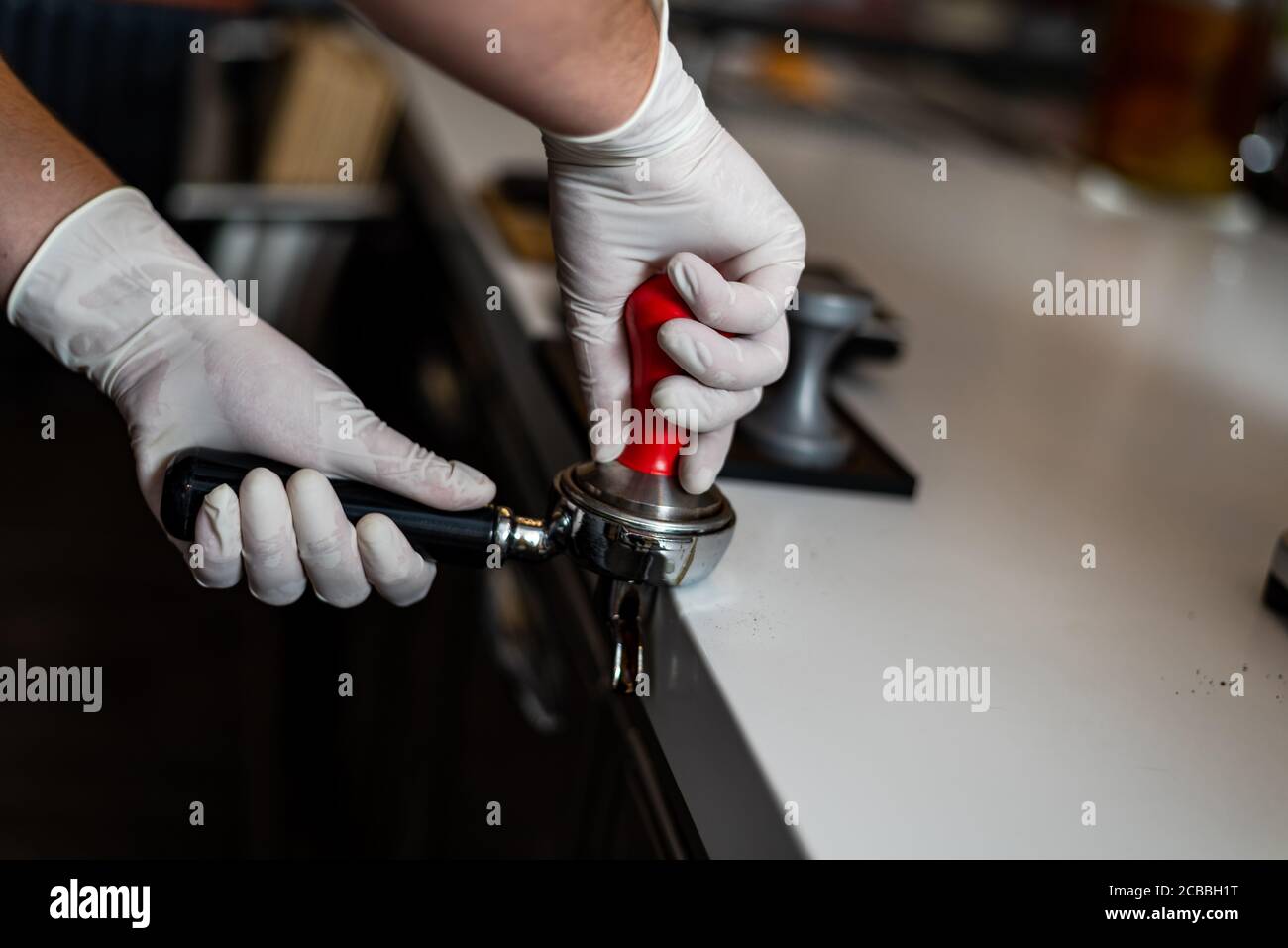 Le barista prépare du café, tient un filtre porta dans ses mains et presse le café. Banque D'Images
